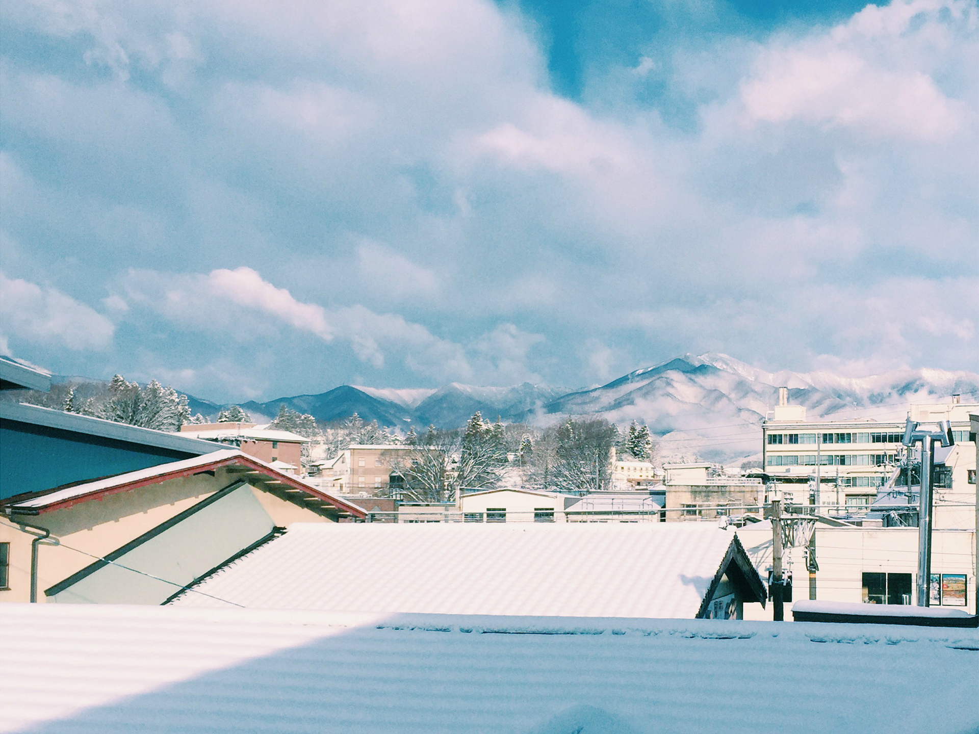 漆戸醸造の敷地内の屋根たちと中央アルプスの山並み